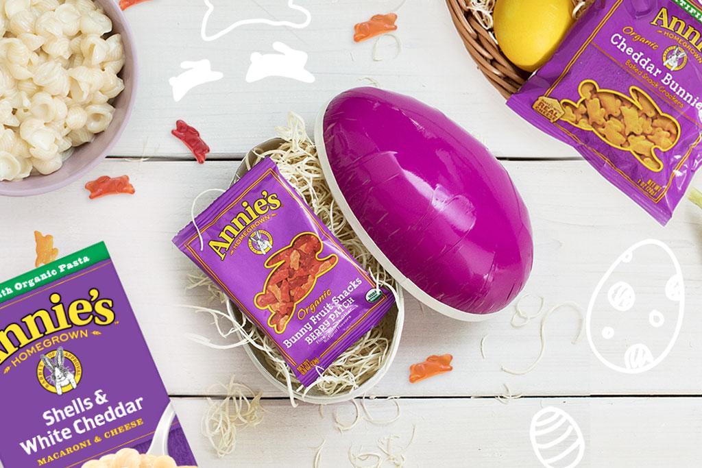 A variety of Annie's products, a purple Easter egg, and three carrots on a white background