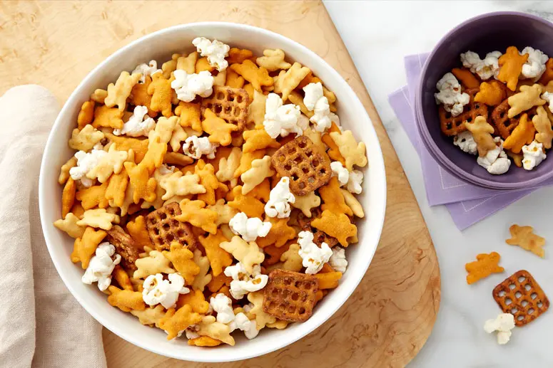 White bowl of Cheddar Bunny Snack Mix recipe on a table.