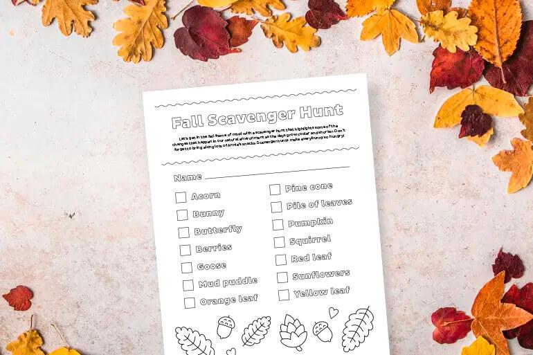 Annie's Fall Scavenger Hunt Activity Sheet on a table of red, orange and yellow leaves.