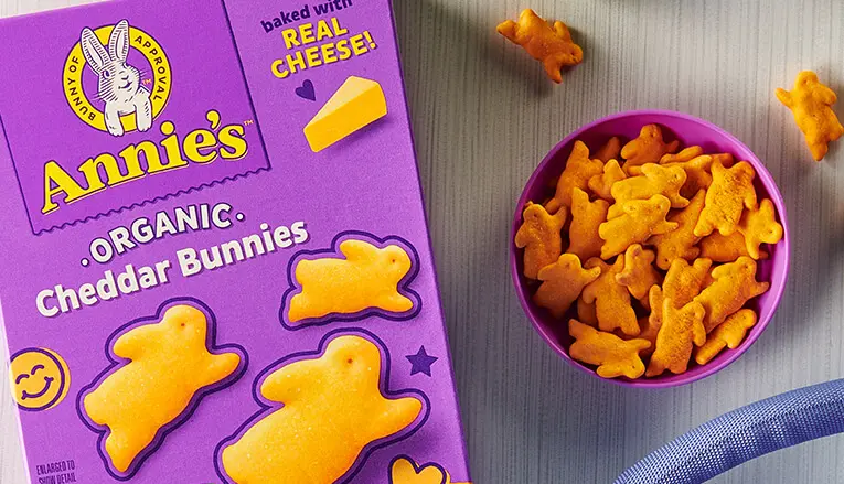 A close up photo of a package front of Annie's Organic Cheddar Bunnies product and a bowl of the next to it.
