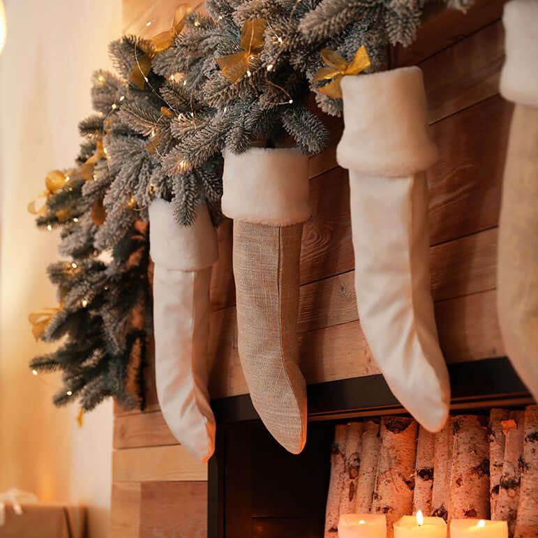 Christmas stockings hanging on a fireplace with green garland and string lights