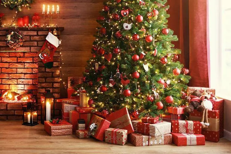 Holiday decorations with a tree and presents in front of a fireplace