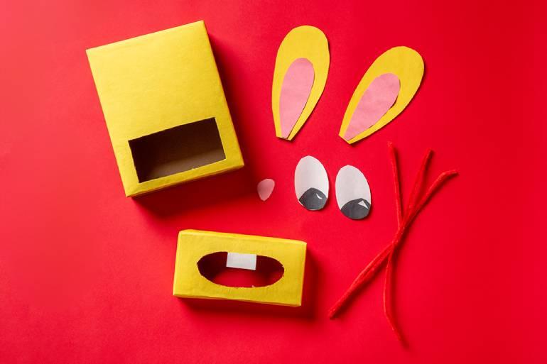 Two yellow boxes with rabbit ears, mouth and eyes on it with pipe cleaner for the whiskers.