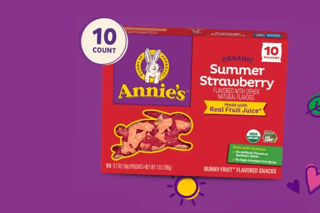 A front of pack box of Annie's Organic Summer Strawberry Bunny Fruit flavored snacks on a purple background with small heart and bunny graphics.